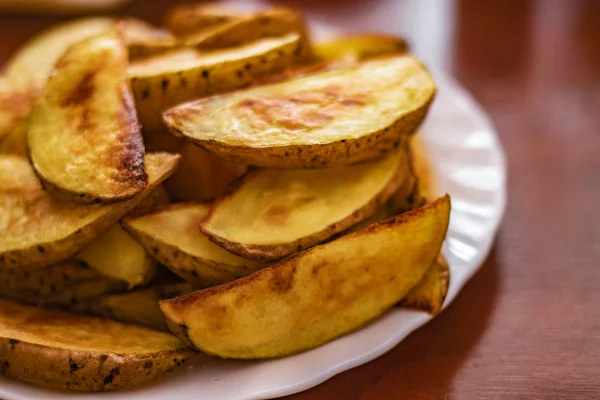 Kızarmış Patates, beyaz tabağın üzerinde ahşap bir masa. Direk tabakta kızarmış patates. Fast Fast Fast Food. altın leziz Patates Düğünleri.