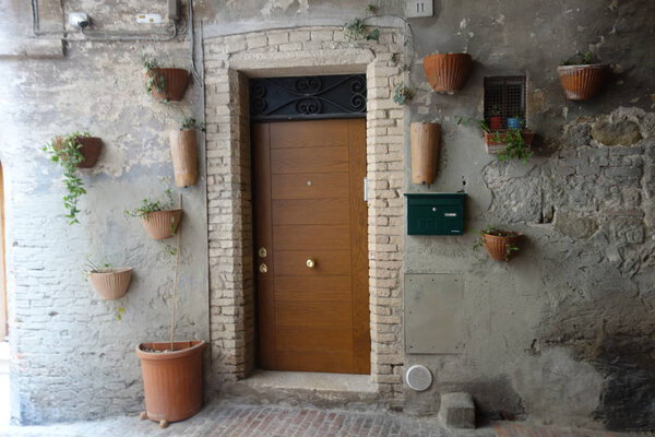 The modern door of a contemporary apartment located on the ground floor of a medieval stone building with details of ceramics and flowers around