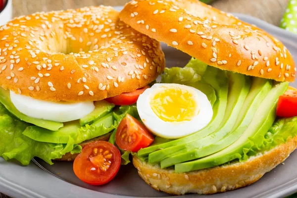 Sandwich de bagel con aguacate, huevo cocido, lechuga de ensalada verde, ta —  Fotos de Stock