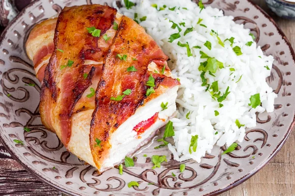 Chicken wrapped in bacon stuffed with soft cheese with rice, tasty homemade dish, beautiful food