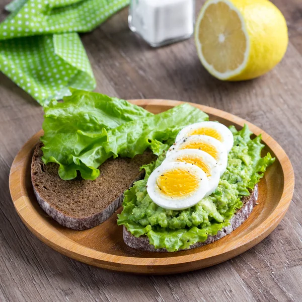 Sandwich con pan, puré de aguacate, huevos en rodajas, ensalada verde, t —  Fotos de Stock