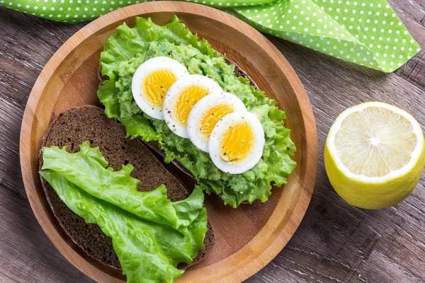 Smörgås med bröd, mosad avokado, skivad ägg, grönsallad, t — Stockfoto