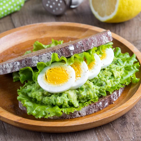 Sanduíche com pão, purê de abacate, ovos fatiados, salada verde, t — Fotografia de Stock