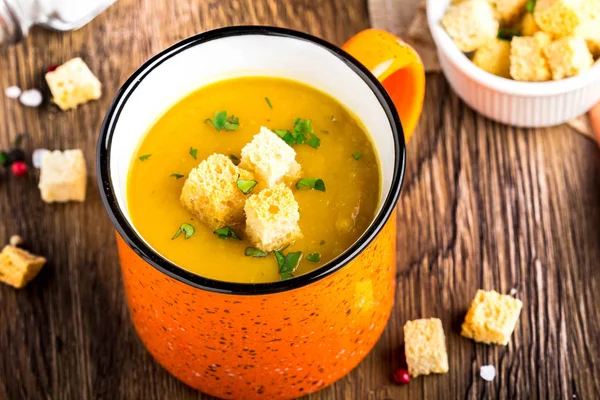 Orange cream soup in cup with croutons, carrot, pumpkin — Stock Photo, Image