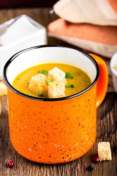 Orange cream soup in cup with croutons, carrot, pumpkin — Stock Photo, Image