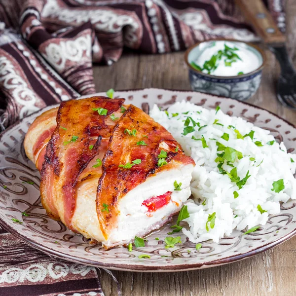 Chicken wrapped in bacon stuffed with soft cheese with rice, tasty homemade dish, beautiful food