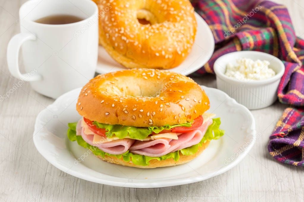 Bagel sandwich with ham, cheese, tomato, green salad lettuce, te