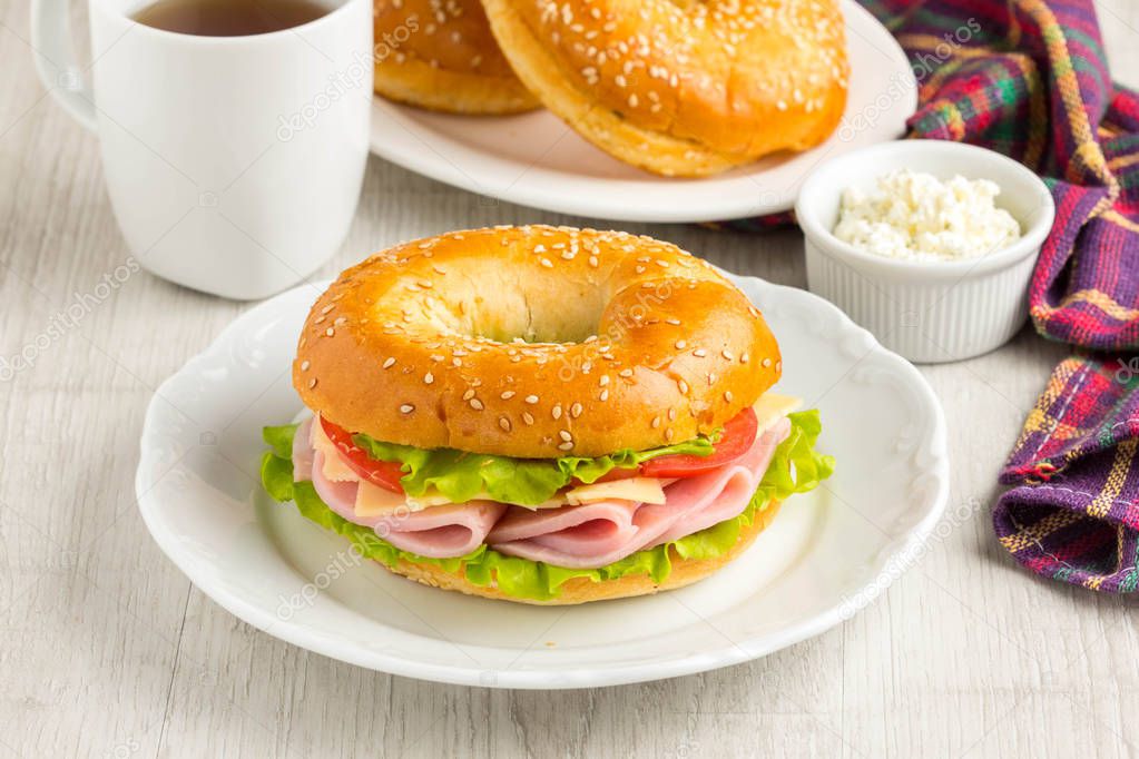 Bagel sandwich with ham, cheese, tomato, green salad lettuce, te