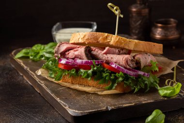 Domatesli, soğanlı, marullu ve hardallı biftekli sandviç.