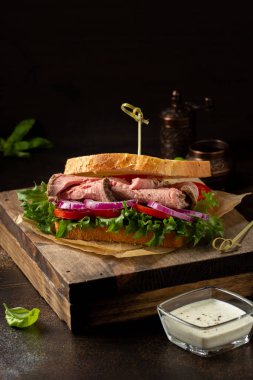 Domatesli, soğanlı, marullu ve hardallı biftekli sandviç.