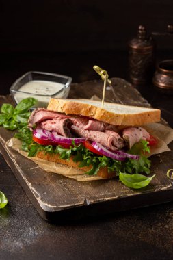 Domatesli, soğanlı, marullu ve hardallı biftekli sandviç.