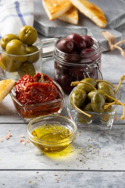 İtalyan antipasti, zeytin, kapari, güneşte kurutulmuş domates, zeytin yağı, ekmek (ciabatta, baget, kızarmış ekmek). Akdeniz yemekleri, lezzetli yemekler, şarap atıştırmalıkları.