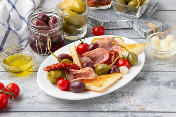 Italian antipasti, olives, capers, sun- dried tomatoes , olive oil, bread (ciabatta, baguette, croutons). Mediterranean assortment of delicious food, wine snacks