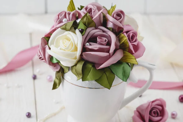 White wooden background with pink flowers, ribbons and beads. Wedding style