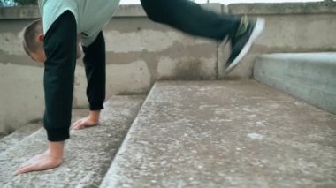 Adam parkour antrenmanı yapıyor. Merdivenlerden kollarıyla iniyordu. Soğuk bir sonbahar gününde. Zekice atladın. Parkour.