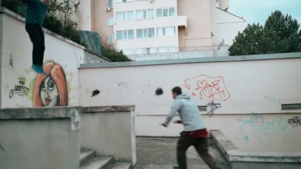 Dos tipos están entrenando a Parkour. Saltar sobre las paredes y barandillas de la ciudad en un día de otoño. Saltando hábilmente hacer un salto mortal. Parkour. — Vídeos de Stock