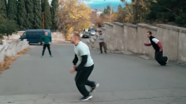 İki adam antrenman parkında. Bir sonbahar günü şehrin duvarlarına ve korkuluklarına atlamak. Akıllıca zıplayarak takla at. Parkour — Stok video