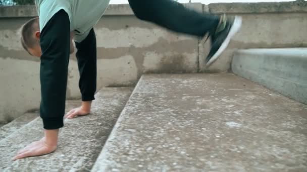 The guy is training parkour. Walking down the stairs in his arms. On a cold autumn day. Cleverly jumping. Parkour. — Stock Video