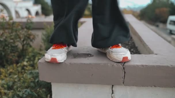 Legs of a guy standing on the wall are blowing a strong wind, the guy is preparing his hands for parkour. Rubs his hands on the sole of old sneakers. — Stock Video