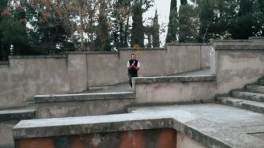 Adam parkour antrenmanı yapıyor. Soğuk bir sonbahar gününde korkuluklara atlıyor. Ters takla atıyor. Zekice atladın. Parkour.
