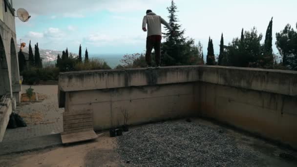 O tipo está a treinar parkour. Salta no corrimão em um dia frio de outono. Faz um backflip. Inteligentemente a saltar. Parkour. . — Vídeo de Stock