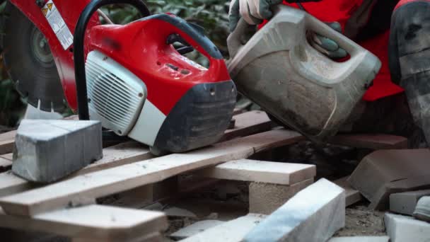 Um trabalhador enche um cortador de concreto combustível para começar a trabalhar na área do parque. 4k — Vídeo de Stock