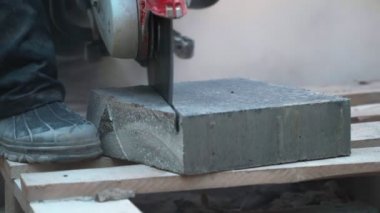 Beton kesme makinesi. Park alanında çalışan bir işçi parkta bir yürüyüş yolu için ağır plakalar kesiyor. Gün boyunca parkta beton kesiminde çalışıyor. Bir sürü toz serpintisi... 4K