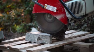 Beton kesme makinesi. Park alanında çalışan bir işçi parkta bir yürüyüş yolu için ağır plakalar kesiyor. Gün boyunca parkta beton kesiminde çalışıyor. Bir sürü toz serpintisi... 4K