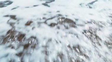 Deniz kumu üzerinde bir kalp çiziliyor ve deniz dalgası çizimleri siliyor. Deniz kumlarında, deniz kıyısında boyanmış bir kalp.