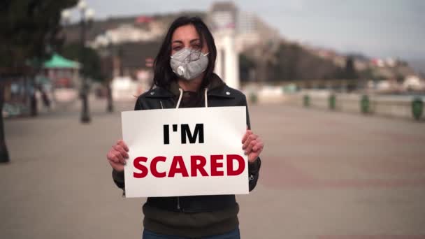 Flicka närbild i staden är i en medicinsk mask med ett tecken - Jag är SCARED — Stockvideo