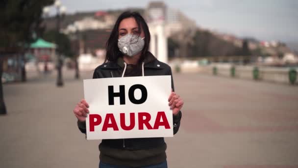 Acercamiento chica en máscara médica sosteniendo un cartel en italiano — Vídeos de Stock