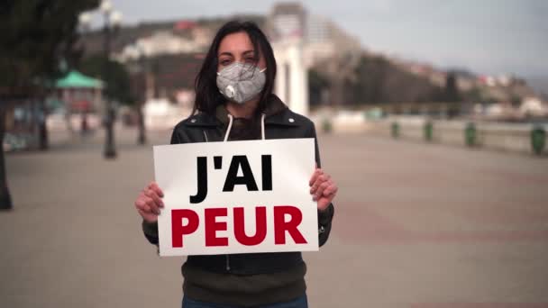 Close-up menina em máscara médica mantém um cartaz em francês — Vídeo de Stock