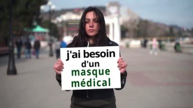 Kapalı çekim kızı, elinde Fransızca bir poster tutuyor.