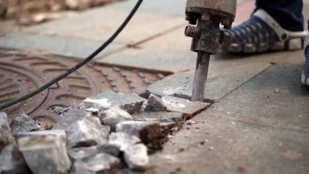 Рабочий отбойного молотка разбивает мраморную плиту вокруг железного люка — стоковое видео