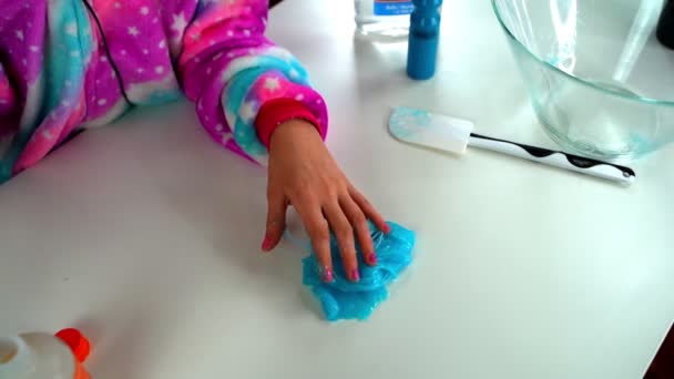 A lány, aki kék nyálkát terít az oldalára. A lány keze nyálkás játékot játszik.. — Stock videók