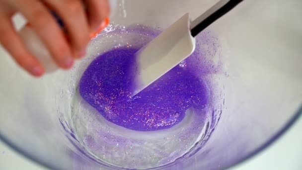 Dívka dělá fialový sliz v misce a mísí — Stock video