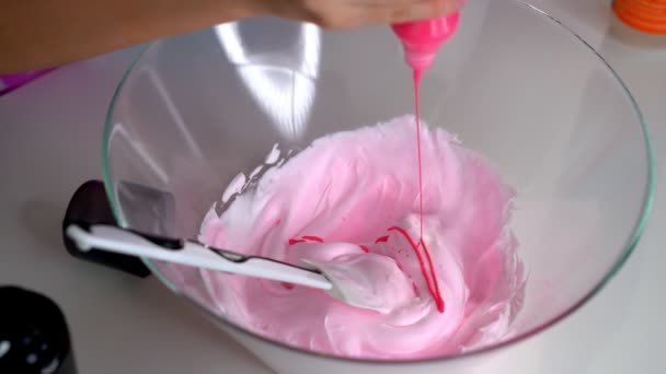 Tangan gadis itu membuat lendir merah muda besar dalam mangkuk di atas meja putih — Stok Video