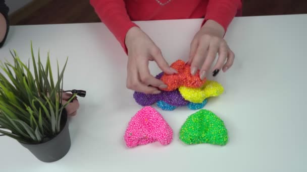 Handen van een meisje dat speelt met dia 's in de vorm van harten, vierkant — Stockvideo