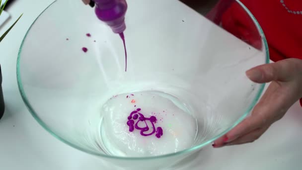 Hände eines Mädchens bilden einen lila Schleim in einer durchsichtigen Schüssel, die sich über sie ergießt — Stockvideo
