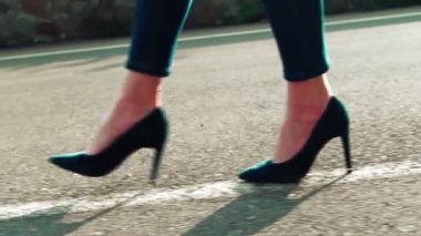 Yüksek topuklu kadın bacakları yol boyunca beyaz bir çizgi boyunca uzanıyor. Stiletto Topukları.