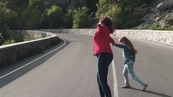 La familia en la naturaleza. Mamá y la hija pequeña van por el camino, ríen, ríen y sonríen. Mamá e hija se cogen de la mano . — Vídeo de stock