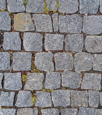 Taş kaldırım dokusu. Granit kaldırım taşlı arka plan. Sert granit kayalar ve biraz ot ve yosun içeren kaldırım taşından bir zemin..