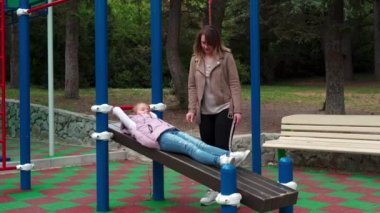 Anne ve kızı açık hava sporları parkında alıştırma yapıyor..