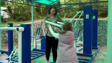 Anne ve kızı açık hava sporları parkında alıştırma yapıyor..