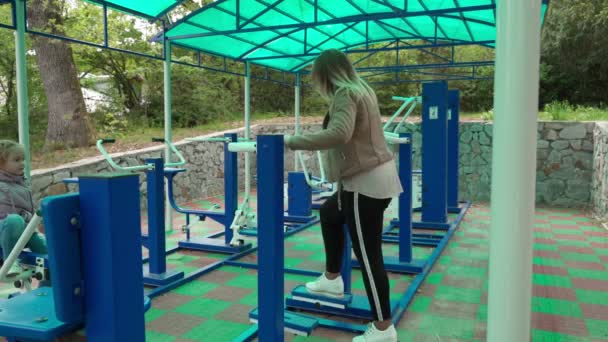 Mother and daughter doing exercises on open air sport playground. — Stock Video