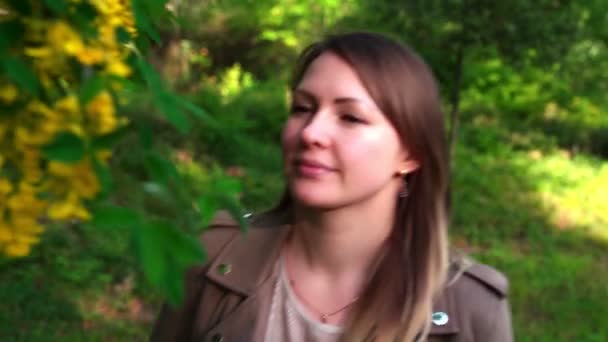 Chica disfruta oliendo fragancia de acacia en primavera — Vídeo de stock