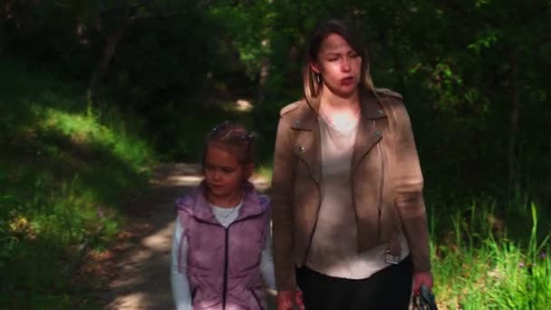 Mom and daughter walk in the spring in the park, walk along the road and talk with each other. — Stock Video