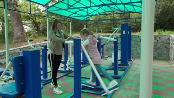 Mother and daughter doing exercises on open air sport playground. — Stock Video