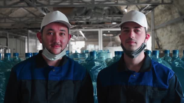 纯净水植物 两名穿着特殊制服 戴着保护面罩的雇员在大水瓶的背景下合影 — 图库视频影像