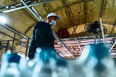 Saf içme suyu bitkisi. Girişimcilik için nakliyeci. Bir işçi su şişelerini alır ve düzenler..